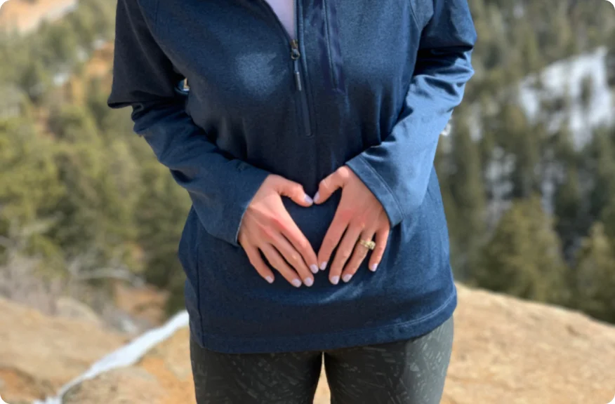 Woman standing with hands on stomach, representing the possibility of meaningful and fulfilling intimate encounters after ostomy surgery.
